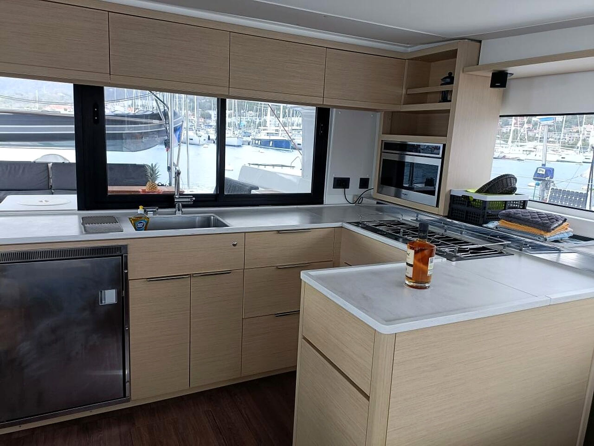 Una cocina moderna con un amplio ventanal, electrodomésticos de acero inoxidable y vistas a un puerto deportivo.