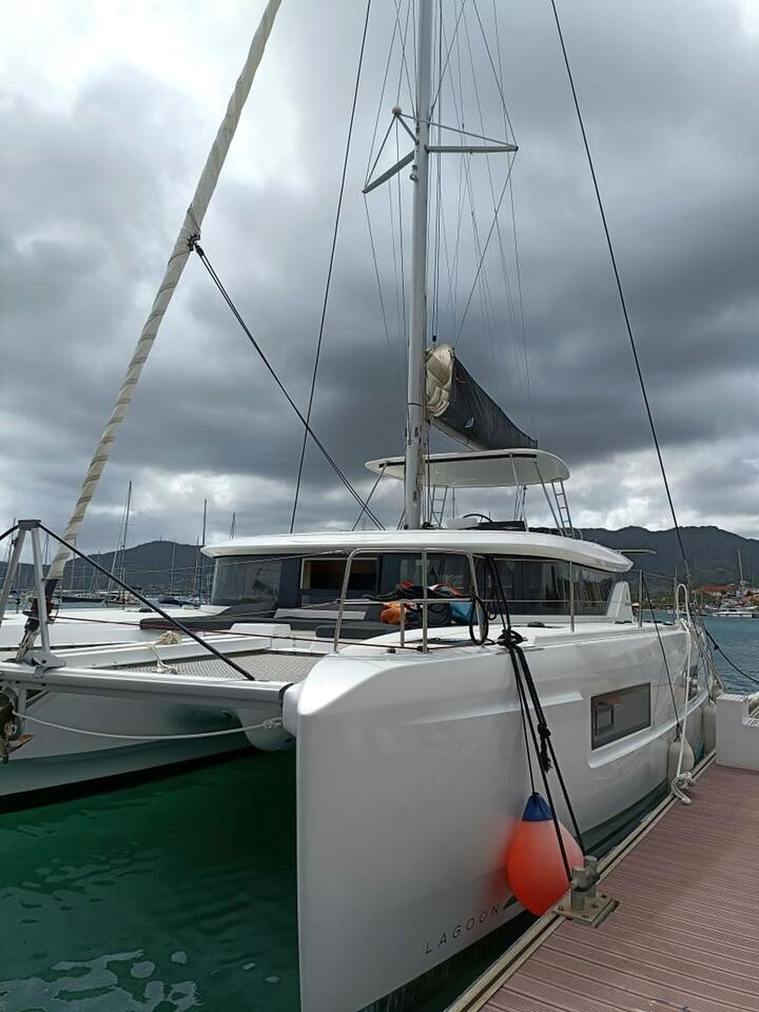 Ein Yachthafen mit einer weißen Yacht, ein klarer Himmel und Berge im Hintergrund.