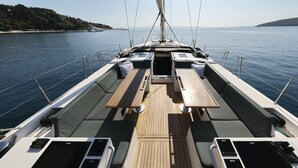 A sailboat deck with a central table, seating, and a view of the sea and coastline. - Sun-Kissed Sailing Adventure in Split, Croatia (Split)