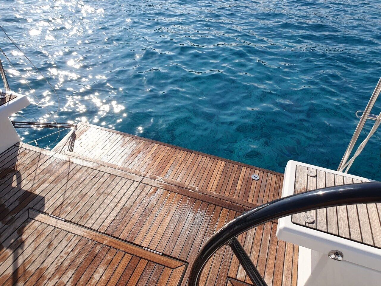 Um deck de madeira com guarda-corpo, dando vista para a água.