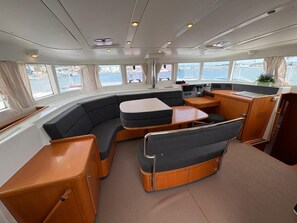 A boat interior with a curved seating area, a small table, and a control panel. - Sibenik Sun and Beach Sailing Extravaganza (Tribunj)