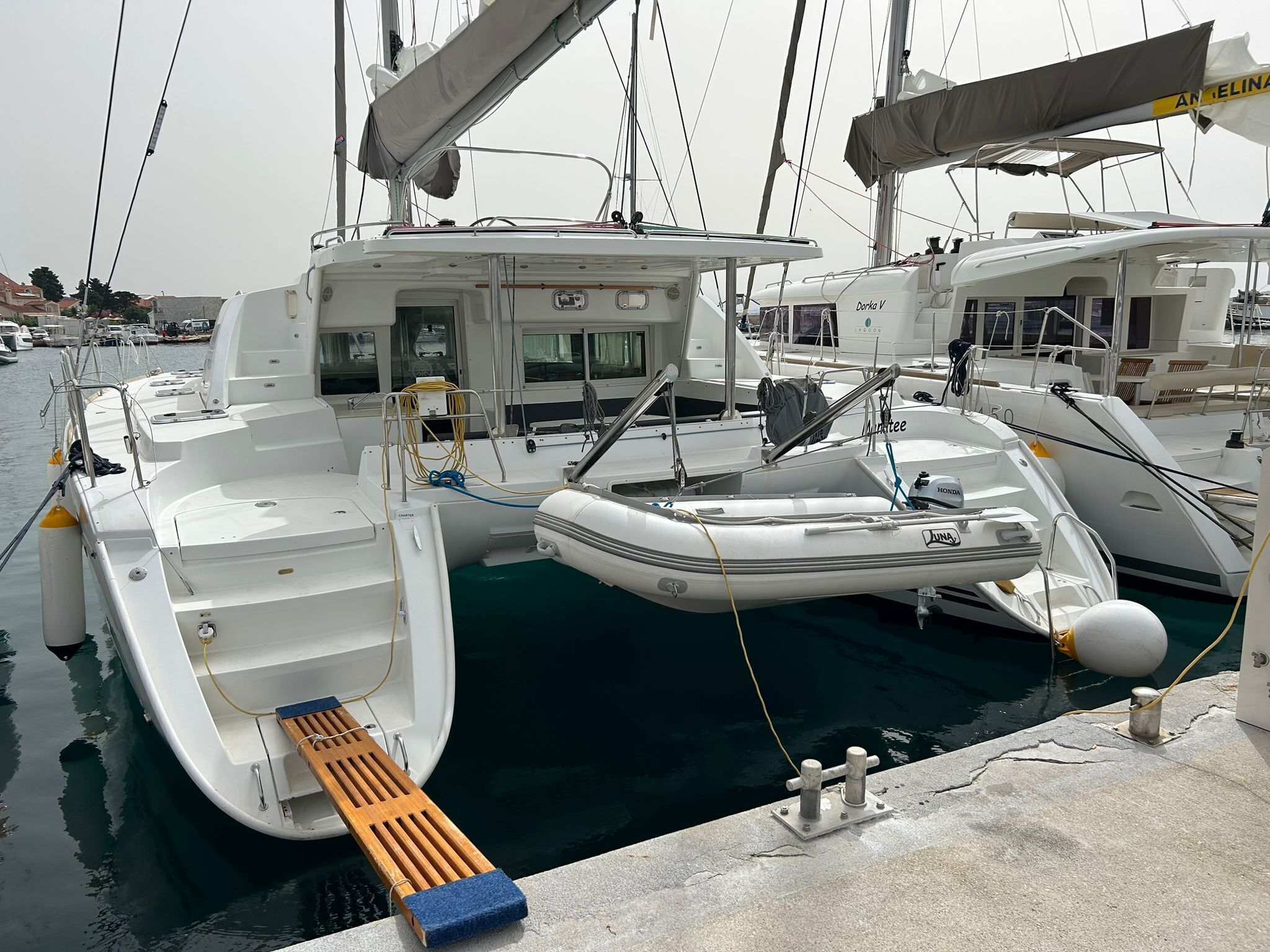 Ein Yachthafen mit mehreren angestückten Booten, darunter ein weißes Motorboot mit Kabine sowie ein kleineres Schlauchboot.