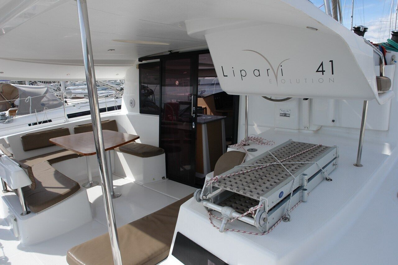 A yacht's deck with a seating area, a table, and a small table with a grid-like surface.