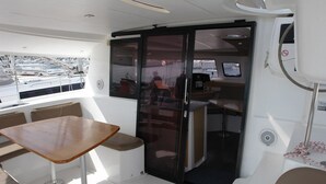 A boat's interior with a table, seating, a sliding door, and a control panel. - Sun-Kissed Sailing Adventure in Northern Croatia (Punat)