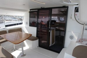 A boat's interior with a table, seating, a sliding door, and a control panel. - Sun-Kissed Sailing Adventure in Northern Croatia (Punat)