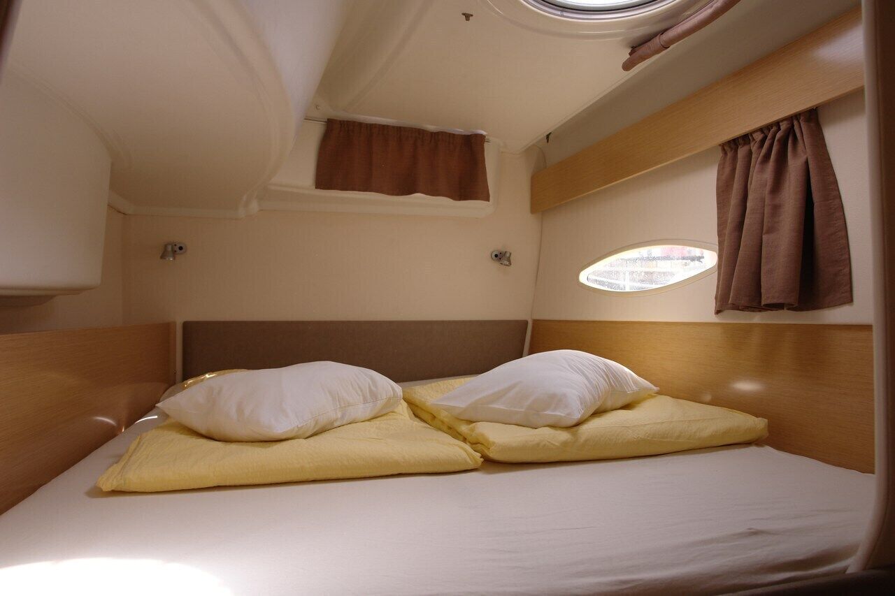 Une petite cabine comprenant un lit simple, une petite fenêtre et une tête de lit.