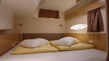 Une petite cabine comprenant un lit simple, une petite fenêtre et une tête de lit.