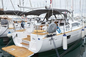 Ein Yachthafen mit mehreren Segelbooten an den Stegen, mit Holzdecks, Rettungsringen und einem überdachten Bereich.