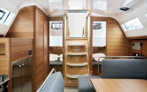 Ein kompaktes Wohnmobil-Interieur mit Küchenzeile, einem Bett, einem kleinen Tisch und einem Fenster.