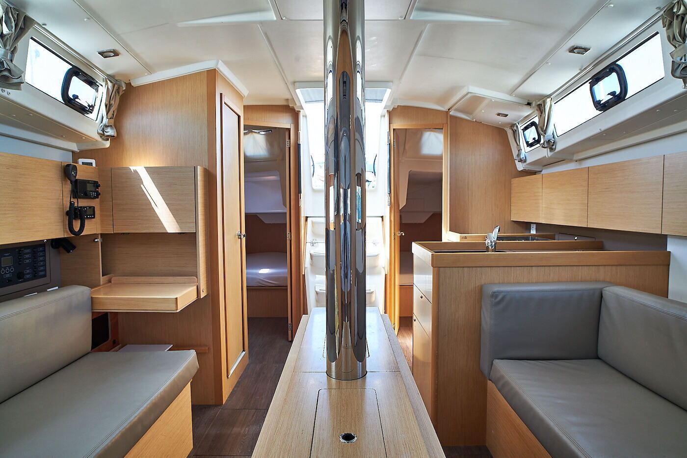A compact interior with a central aisle, wooden cabinetry, a small kitchenette, and seating areas.