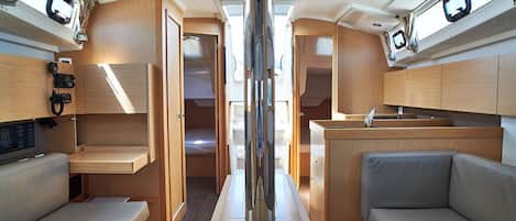 Un interior compacto con un pasillo central, armarios de madera, una pequeña kitchenette y zonas de estar.