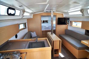 A compact interior with a kitchenette, seating area, and a TV mounted on the wall. - Sun-Kissed Sailing Adventure in Zadar, Croatia (Biograd na moru)