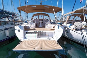 Eine Yacht mit Holldeck, einer Kabine mit dem Namen 'ESCAPE II' und einer Flagge.