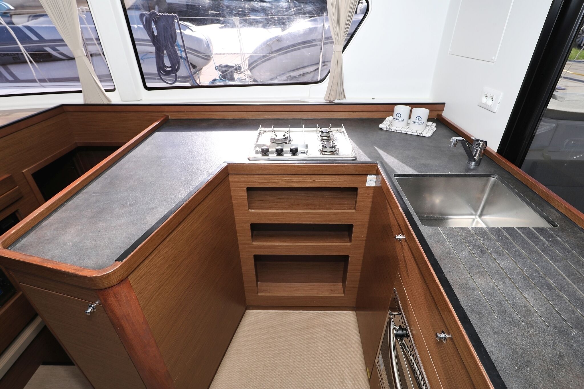 A compact galley with a stove, sink, and storage drawers.