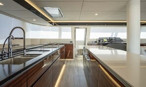 A modern kitchen with a central island, stainless steel appliances, and a view of the city. - Sun-Kissed Sailing Adventure in Split, Croatia (Kaštel Gomilica)