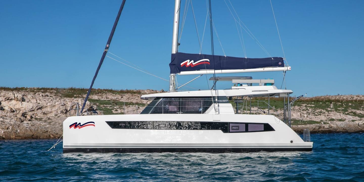 A white yacht with a streamlined design, a cabin, and a sail.