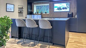 A modern kitchen with a bar area, bar stools, a window with a view, and a countertop with various items. - Awesome home in Lycksele with house sea view (Lycksele)