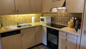 Una cocina con armarios de madera, microondas, lavavajillas y estufa.