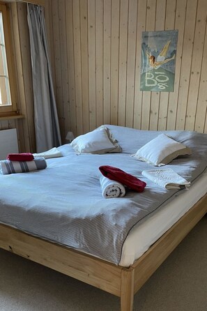 A wooden-paneled room with a bed, pillows, a rolled towel, and a towel on the bed. - Halten (Hofmann) Appartement/Fewo, Bad, WC, 2 Schlafräume 4-Bettwohnung by Interhome (Zweisimmen)