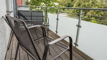 Un balcón con sillas y una mesa de metal, con vistas a un paisaje verde.