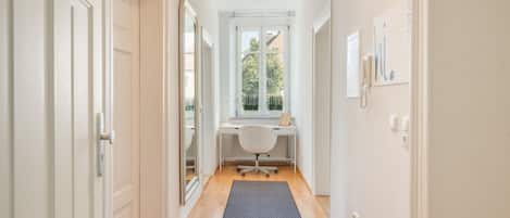 Un couloir avec un bureau, une chaise et une fenêtre donnant sur un paysage verdoyant.