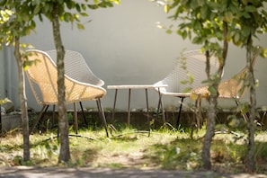 Two wicker chairs with metal legs, positioned on a concrete surface, surrounded by grass and trees. - Stadt Land Fluss Apartment 2 (Regensburg)