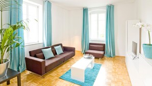 A modern living room with a brown sofa, a white coffee table, and a potted plant. - Stadt Land Fluss Apartment 2 (Regensburg)