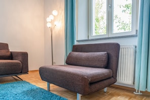 A modern living room with a brown sofa, a blue rug, and a floor lamp. - Stadt Land Fluss Apartment 2 (Regensburg)