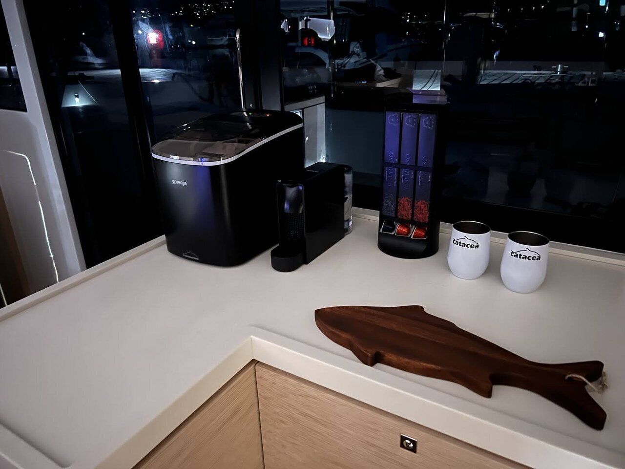 Eine Küchenarbeitsplatte mit einer Kaffeemaschine, zwei weißen Tassen und einer Holz-Fischdekoration.