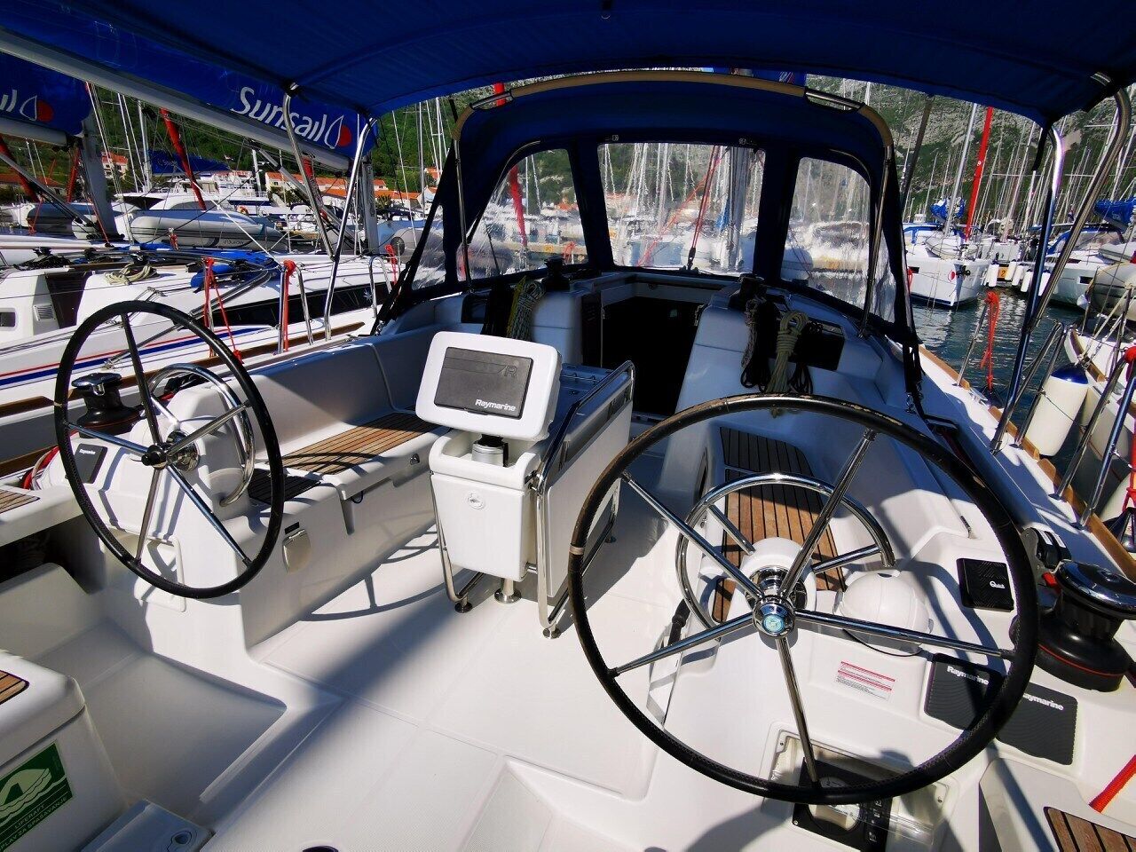 A boat's deck with a steering wheel, a control panel, and a canopy.
