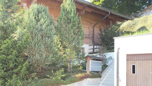 Un edificio con fachada de madera, una escalera de concreto y una pequeña estructura de madera con una lámpara.