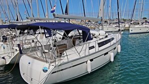 En vit yacht låg förtöjd vid en småbåtshamn, och i bakgrunden syntes flera andra yachter.