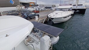 Ein Yachthafen mit vertäuten Booten, einem Solarmodul und einem in der Nähe geparkten Auto.