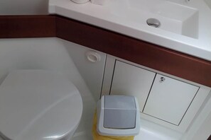 Eine weiße Toilette, ein weißes Waschbecken und ein Mülleimer in einem Badezimmer.