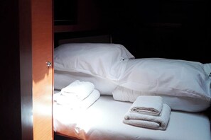 Ein ordentlich bezogenes Bett mit weißen Leinen und gefalteten Handtüchern.