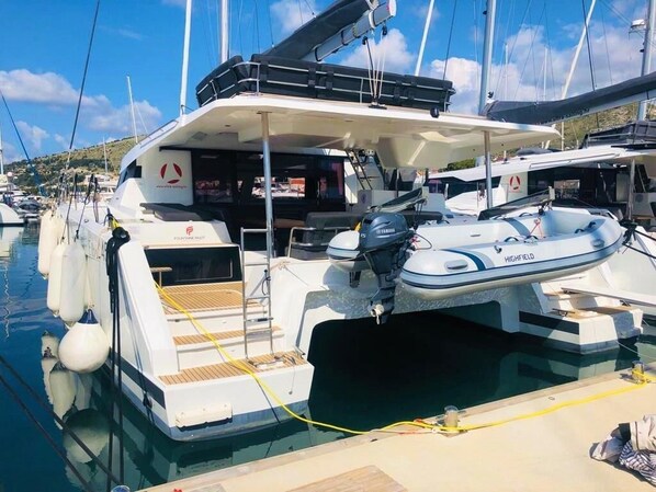 Un yacht était amarré dans une marina, avec une terrasse couverte, un moteur hors-bord Yamaha et le nom de la marque « HIGHFIELD » visible sur le côté.