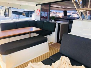 Un intérieur de bateau moderne comprenant un coin repas, des sièges et une vue sur le port de plaisance.