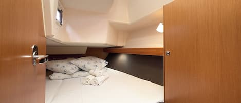 Una cabaña compacta con una cama, un pequeño rincón de descanso y un televisor montado en la pared.