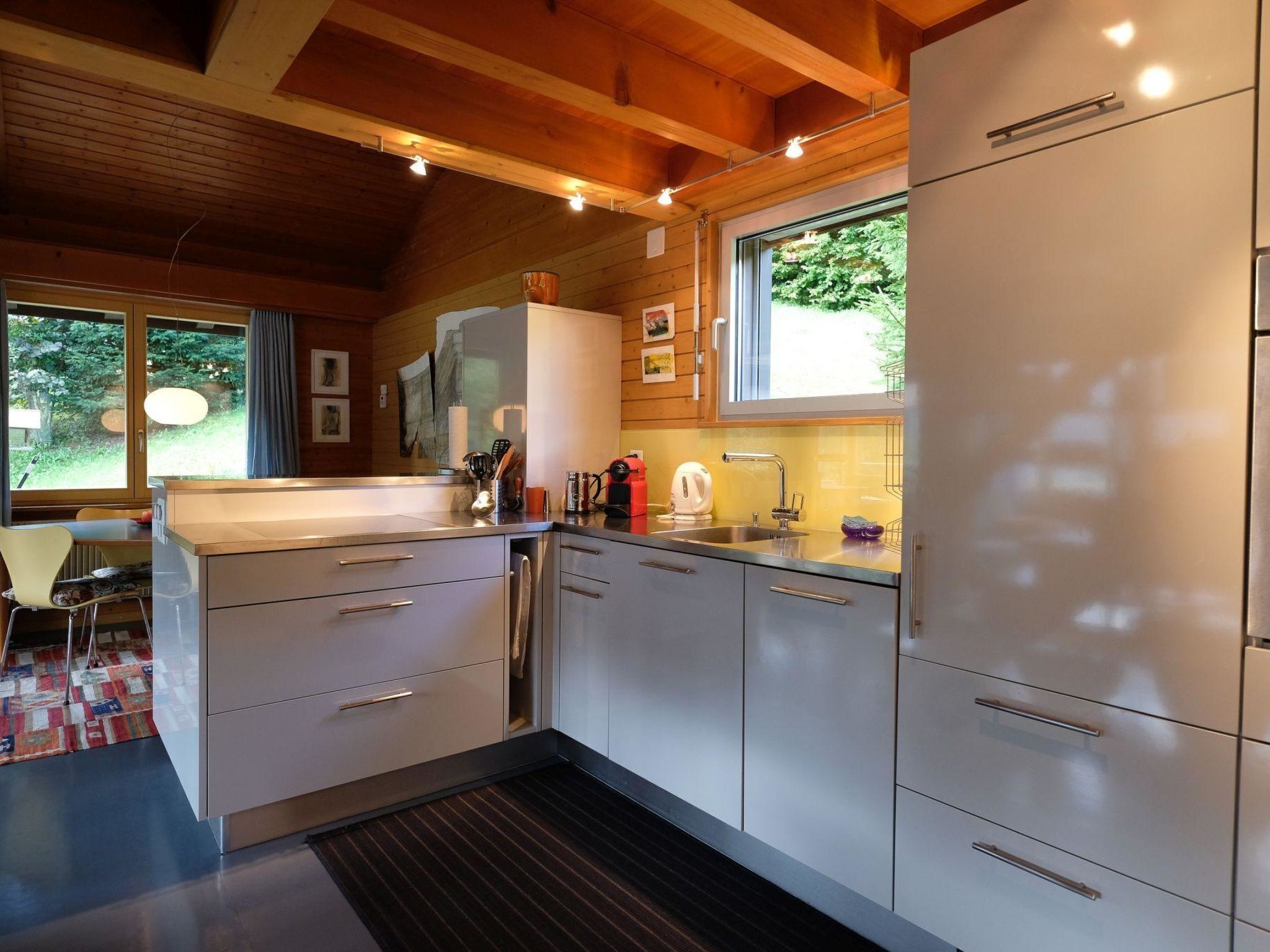 Una cucina moderna con elettrodomestici in acciaio inossidabile, travi a soffitto in legno e un'ampia finestra che garantisce luce naturale.