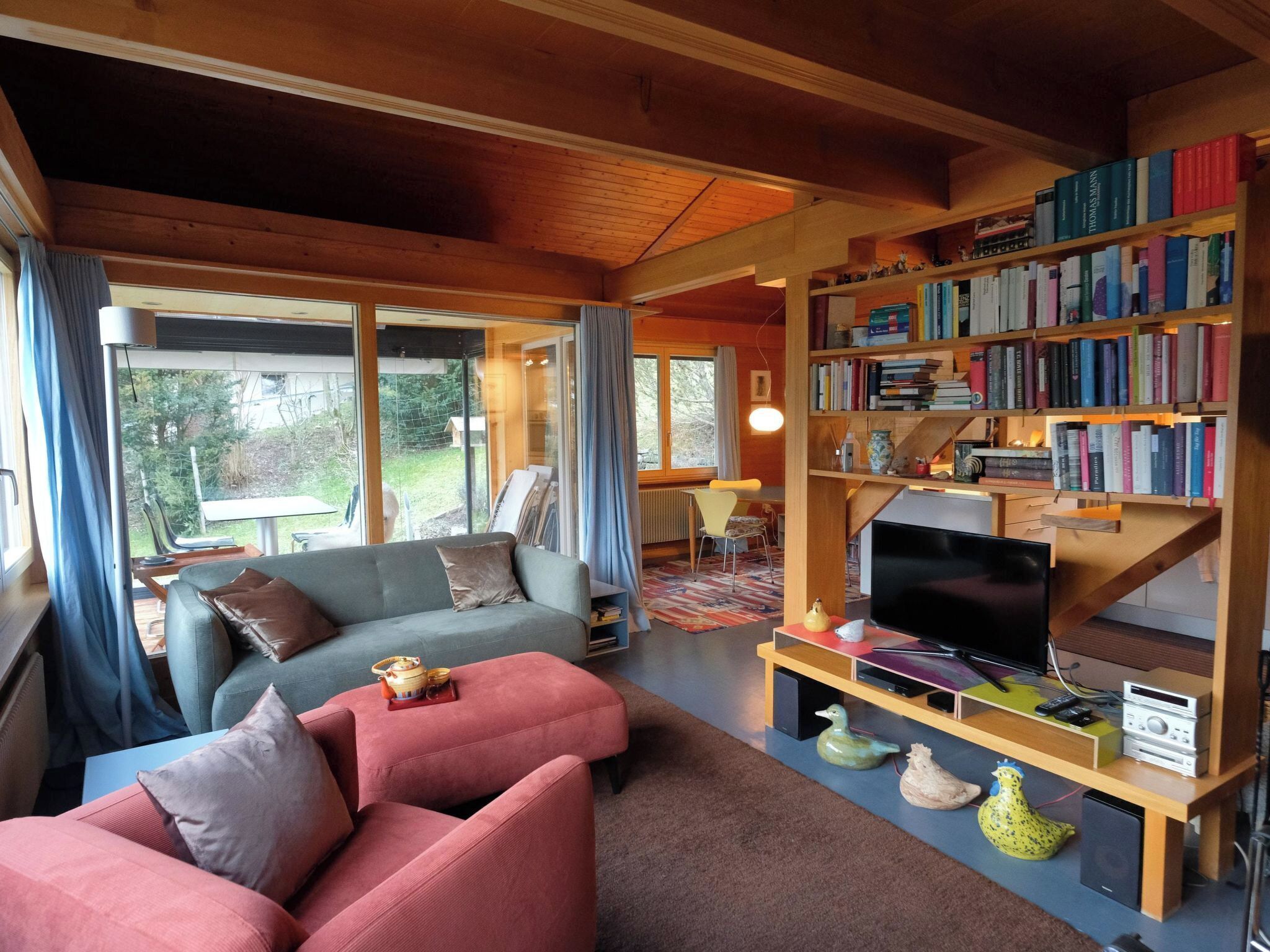 A cozy living room with a sofa, chairs, a bookshelf, a television, and a dining area.