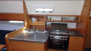 A compact kitchenette with a sink, stove, and storage cabinets.