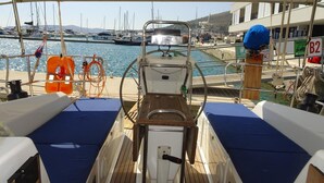A boat deck with a steering wheel, life rings, and a view of the marina.
