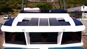 Una barca con una zona di copertura sul ponte, pannelli solari e una cabina con finestre.