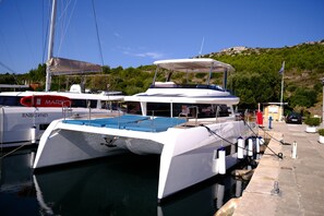 A marina with boats docked, a clear sky, and a hilly landscape in the background. - Sun-Kissed Sailing Adventure in Sibenik, Croatia (Primošten)