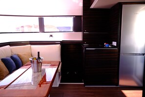 Een compacte keuken met een koelkast, een klein aanrecht en een raam dat voor natuurlijk licht zorgt.