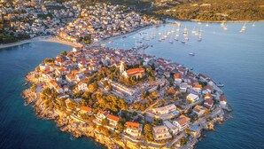 Vista aerea di una cittadina costiera con un’isola centrale caratterizzata da edifici residenziali e commerciali, circondata da una marina con imbarcazioni.