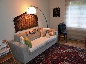Un salon avec un canapé, un tapis à motifs, une lampe et un fauteuil.