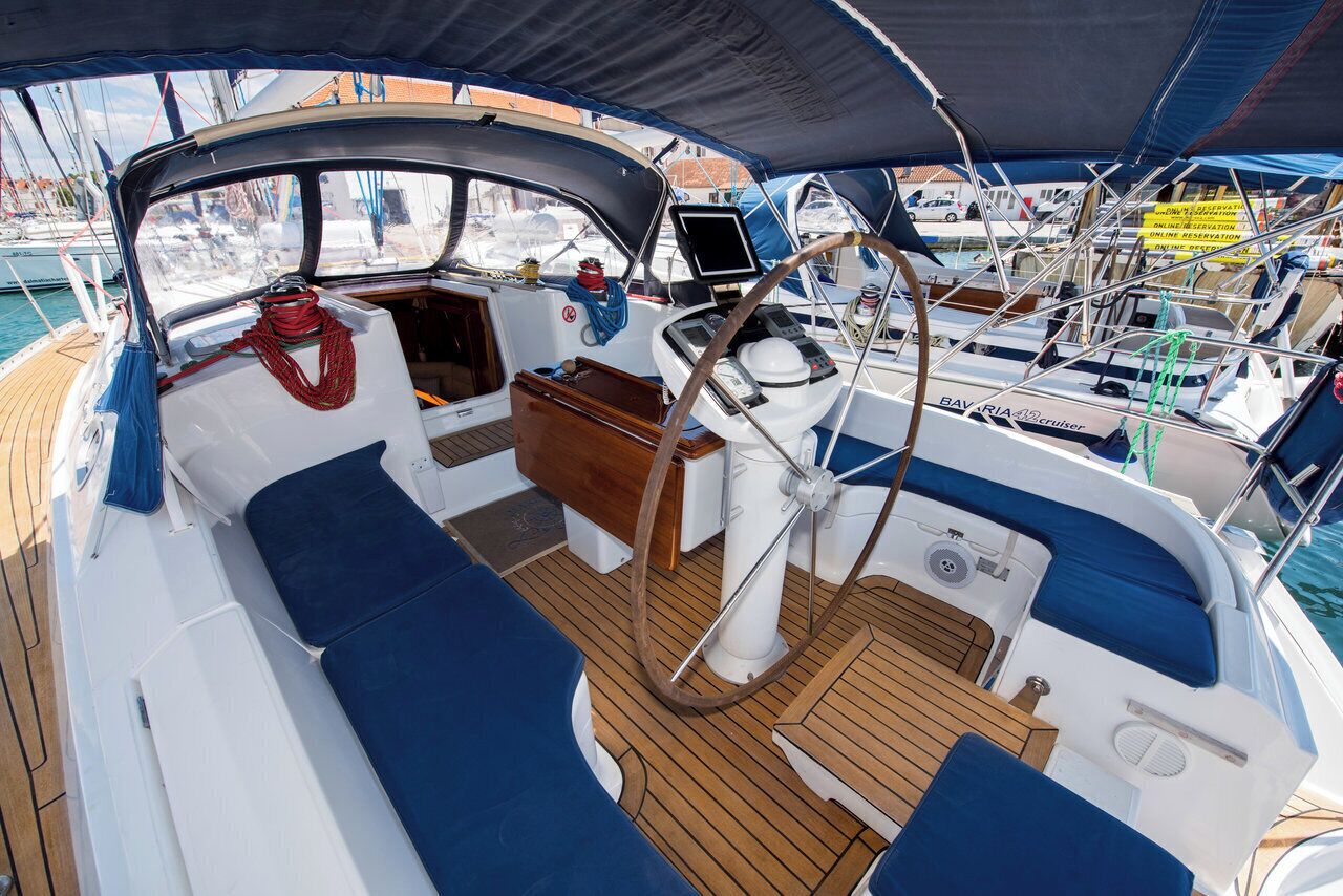 A boat deck with a steering wheel, control panel, and seating area.