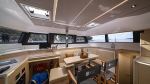 L’intérieur d’un yacht comprend un coin repas, une petite cuisine et un espace salon avec vue sur l’eau.
