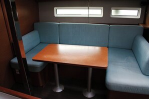 A compact interior with a wooden table and blue cushioned seating. - Dubrovnik Delight: A Sun-Kissed Sailing Experience (Komolac)